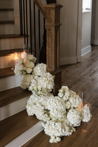 Simple, white flowers line the base of stairs in a modern white aesthetic home for a wedding ceremony. Timeless indoor wedding in Dallas, captured with a refined, editorial approach by DFW documentary wedding photographer.