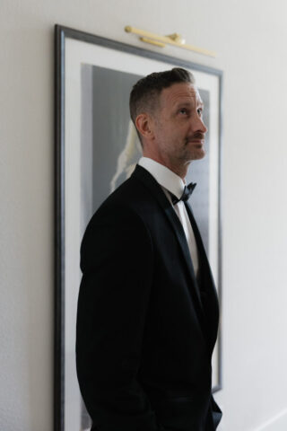 A groom looks affectionately at his bride as she walks down the stairs during their private first look. Timeless indoor wedding in Dallas, captured with a refined, editorial approach by DFW documentary wedding photographer.