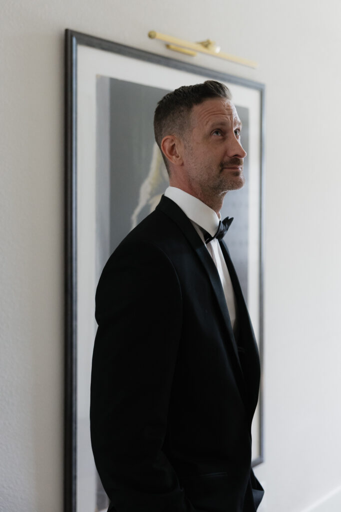 A groom looks affectionately at his bride as she walks down the stairs during their private first look. Timeless indoor wedding in Dallas, captured with a refined, editorial approach by DFW documentary wedding photographer.