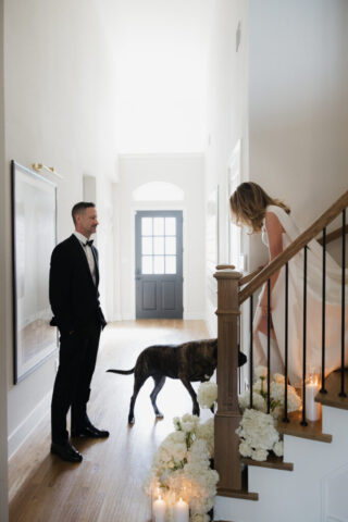 A groom looks affectionately at his bride as she walks down the stairs during their private first look. Timeless indoor wedding in Dallas, captured with a refined, editorial approach by DFW documentary wedding photographer.