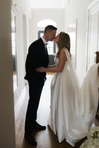 A groom looks affectionately at his bride as she walks down the stairs during their private first look. Timeless indoor wedding in Dallas, captured with a refined, editorial approach by DFW documentary wedding photographer.