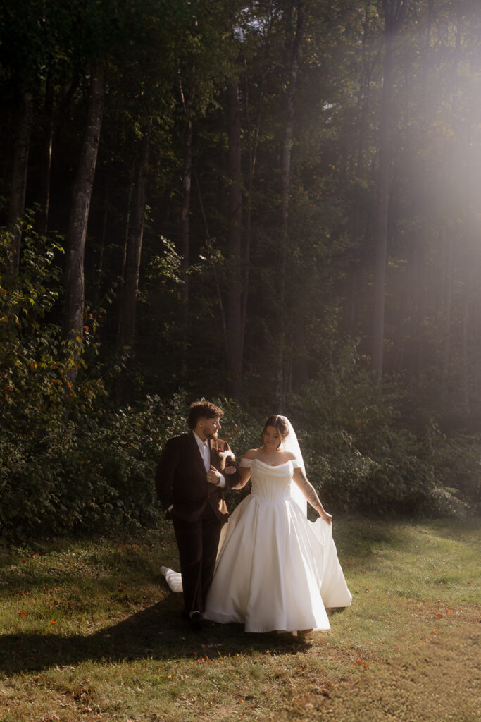 Bride and groom walking in a sunlit forest clearing