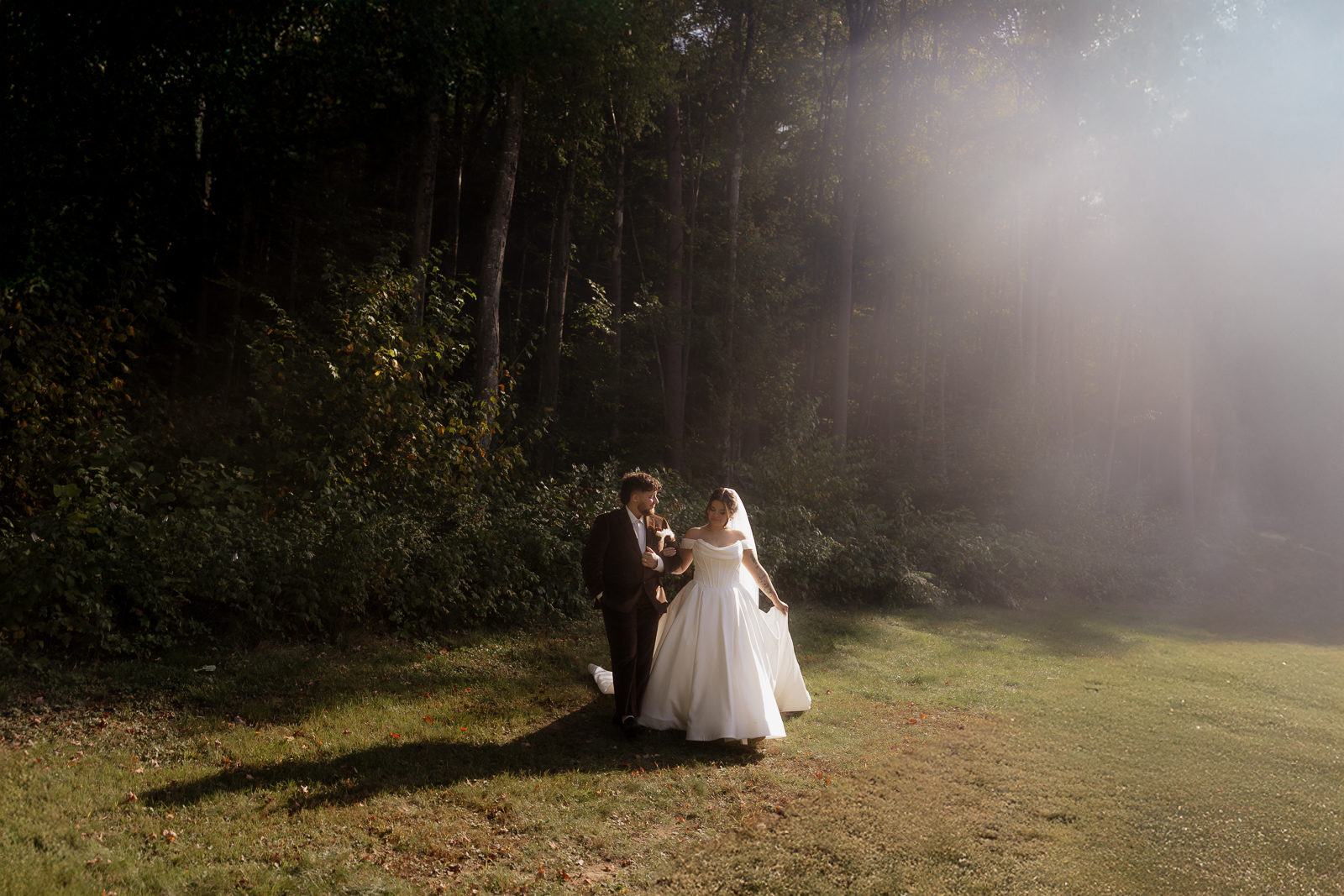 Bride and groom walking in a sunlit forest clearing