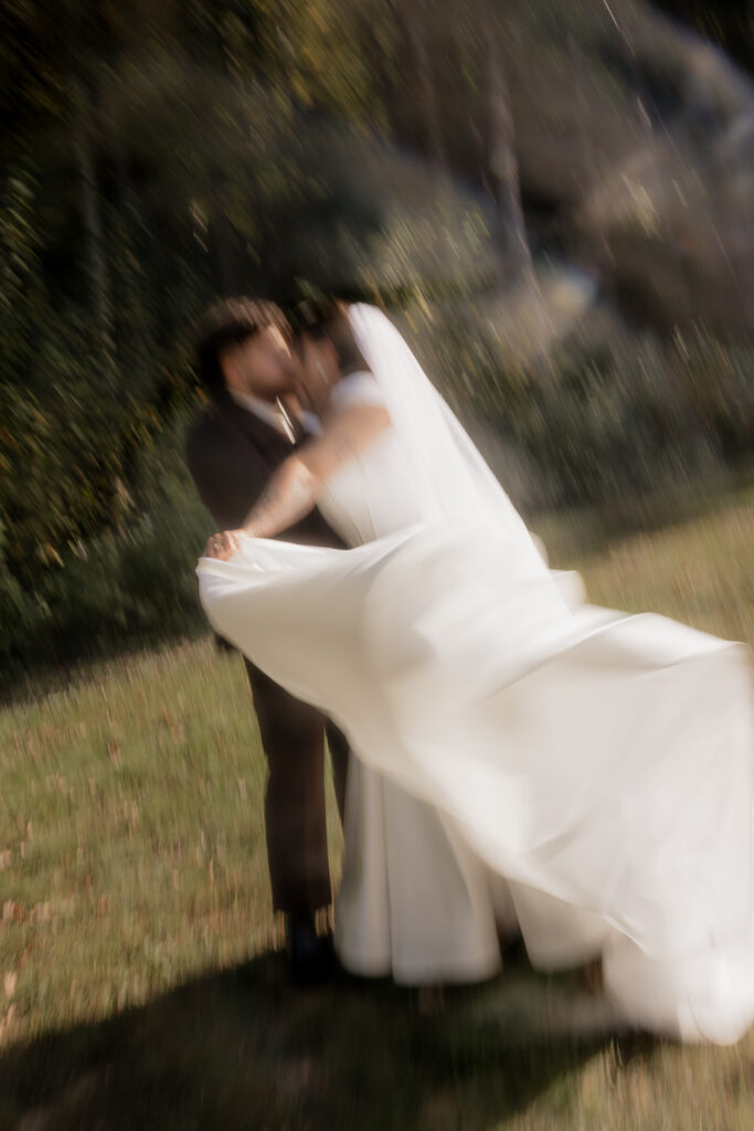 Blurry wedding photo of a couple kissing outdoors