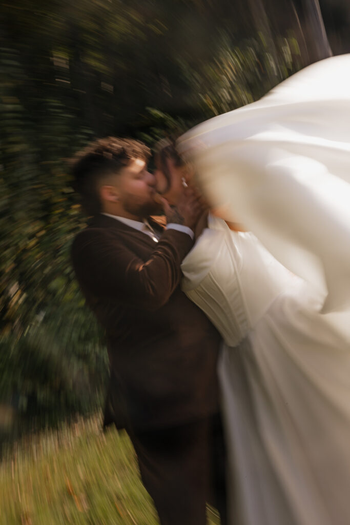 Artistic blurry wedding photo of couple kissing outdoors