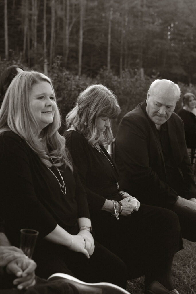 Three people sitting quietly outdoors during a sentimental moment at an event.