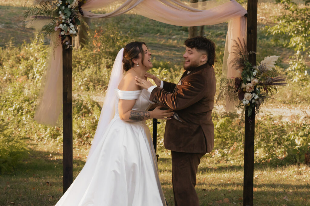 Bride and groom laughing during outdoor wedding ceremony