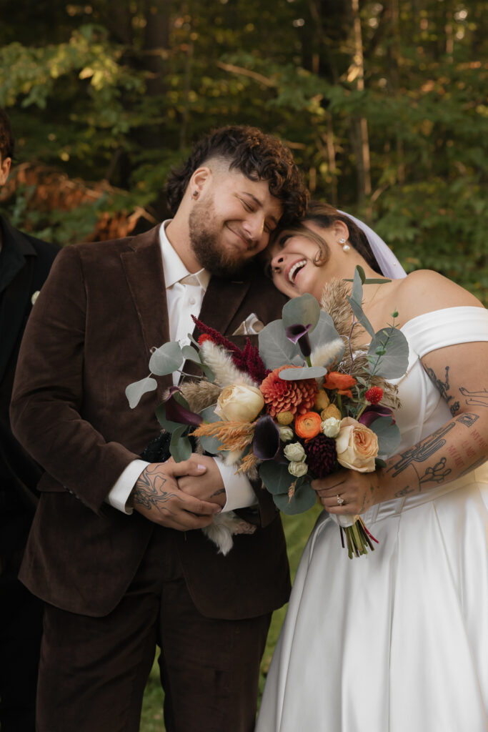 A couple smiling warmly while embracing, with a colorful bouquet.