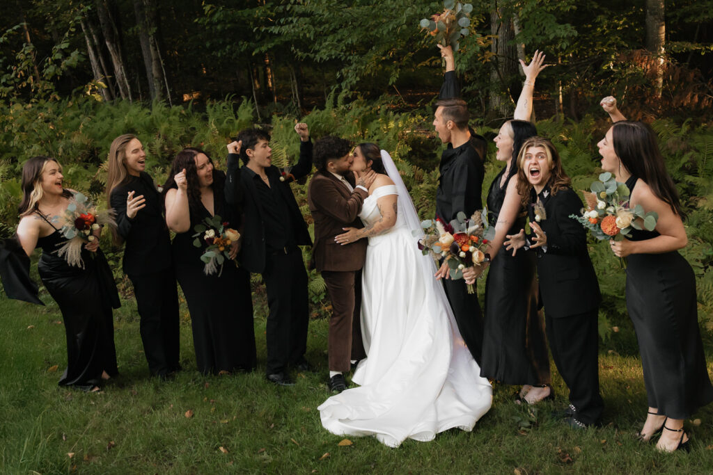 Wedding party celebrating as couple kisses outdoors