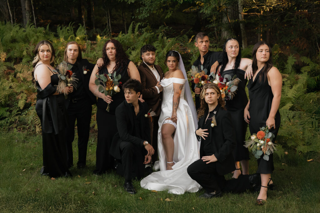 Bridal party in elegant outfits posing in a lush forest setting.