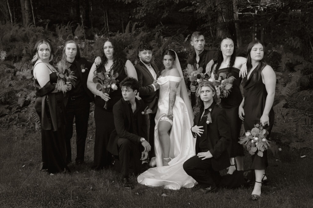 Black and white group wedding photo with bride and guests in formal attire.