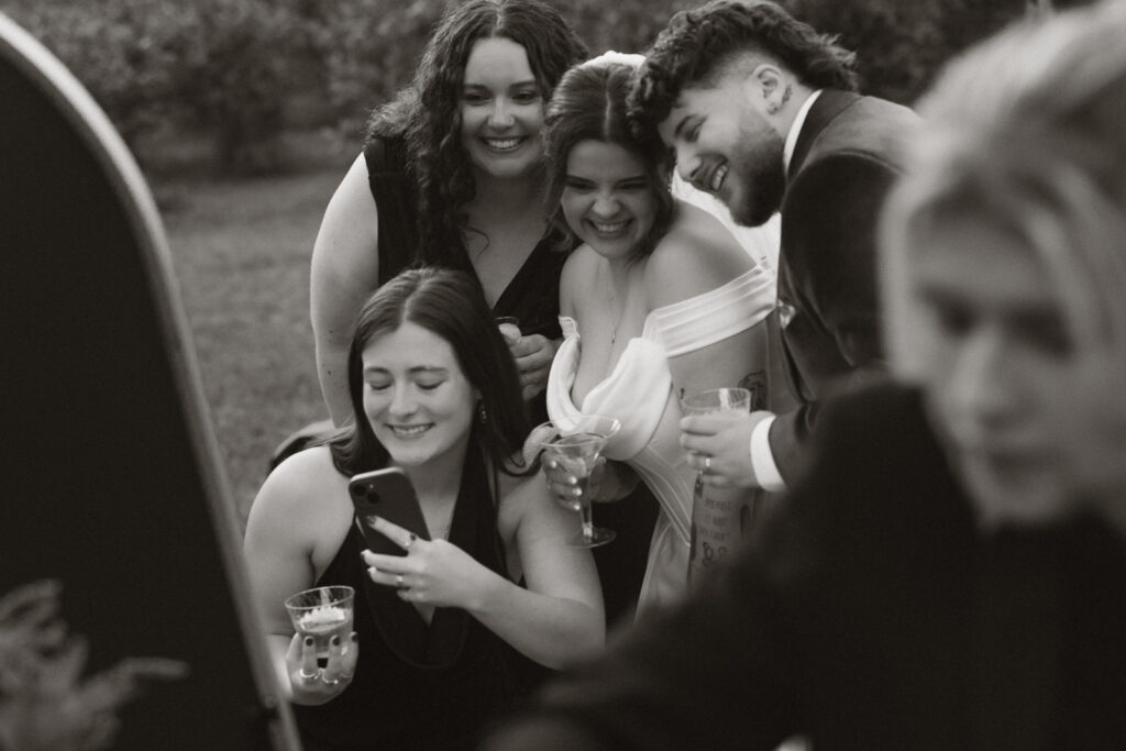 Group of four smiling friends taking a selfie at an outdoor event