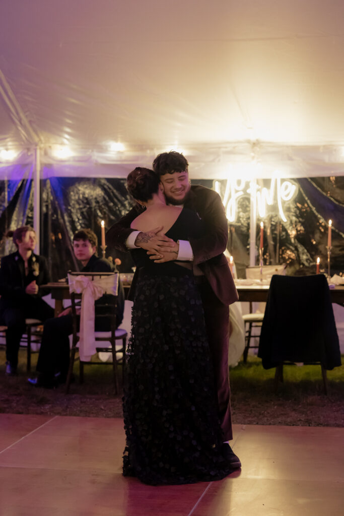 A couple embraces during a dance at an outdoor evening event with soft ambient lighting.