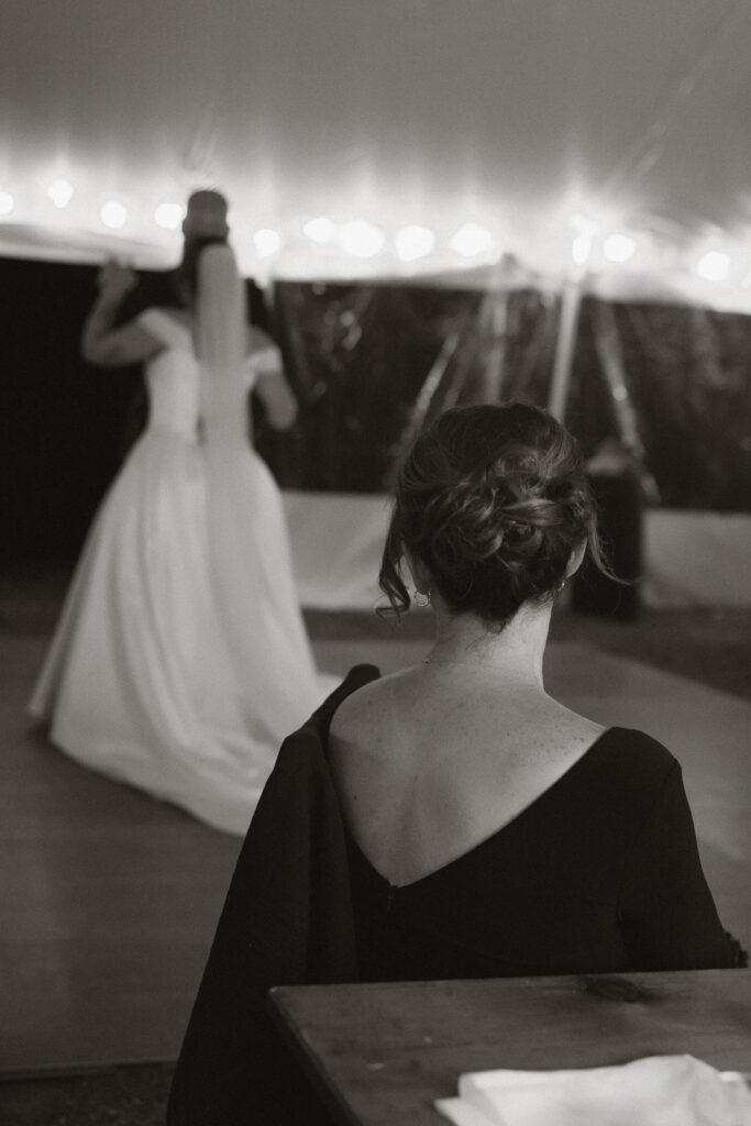 Back view of a woman at a wedding reception, watching a bride dance.