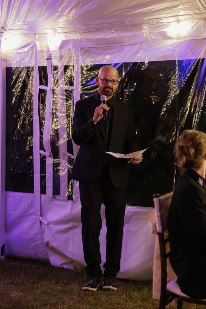 Man in suit giving speech with microphone and paper