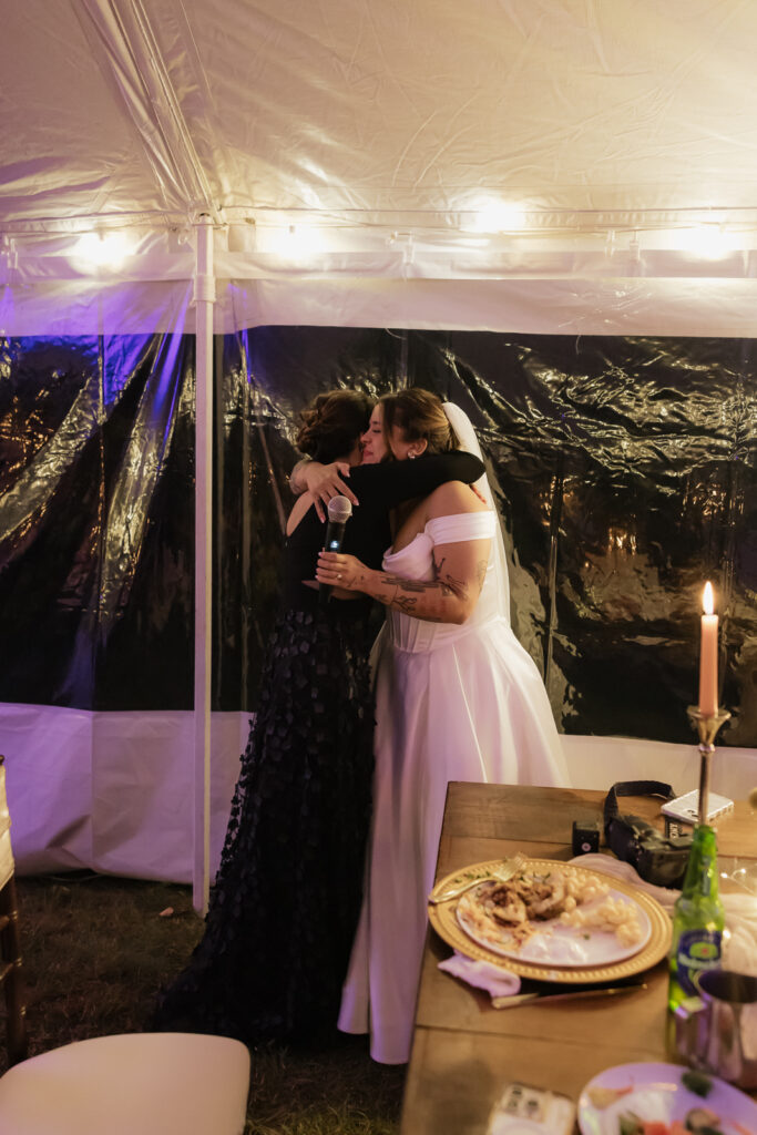 Two women hugging under a tent at an event