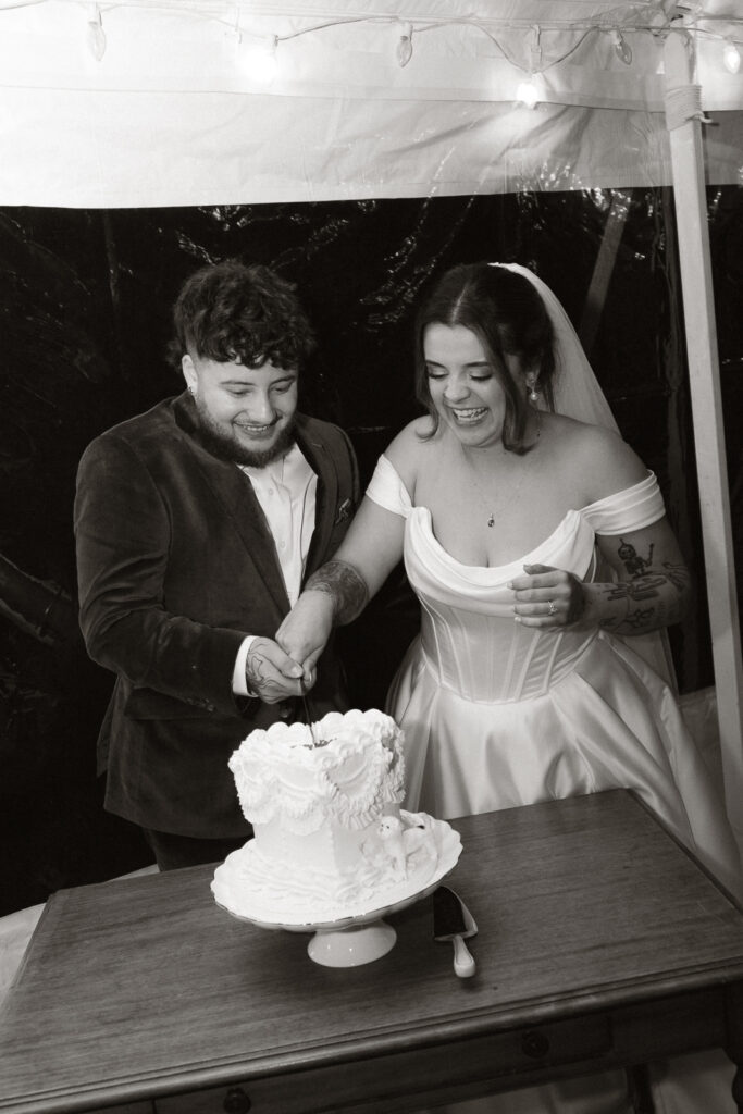 Bride and groom smiling while cutting wedding cake