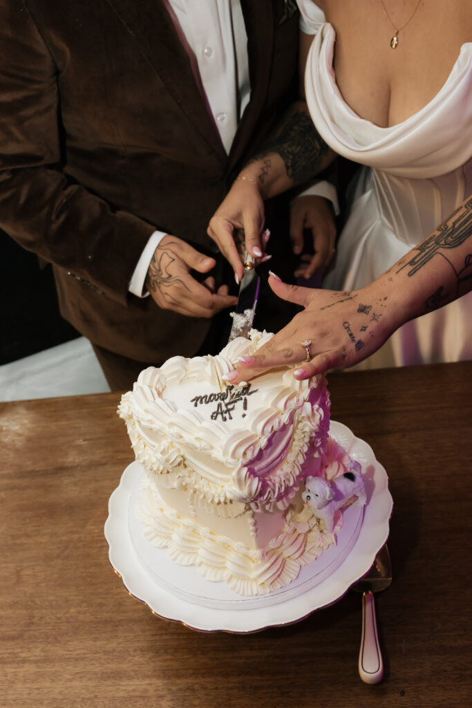 Couple cutting wedding cake with white icing