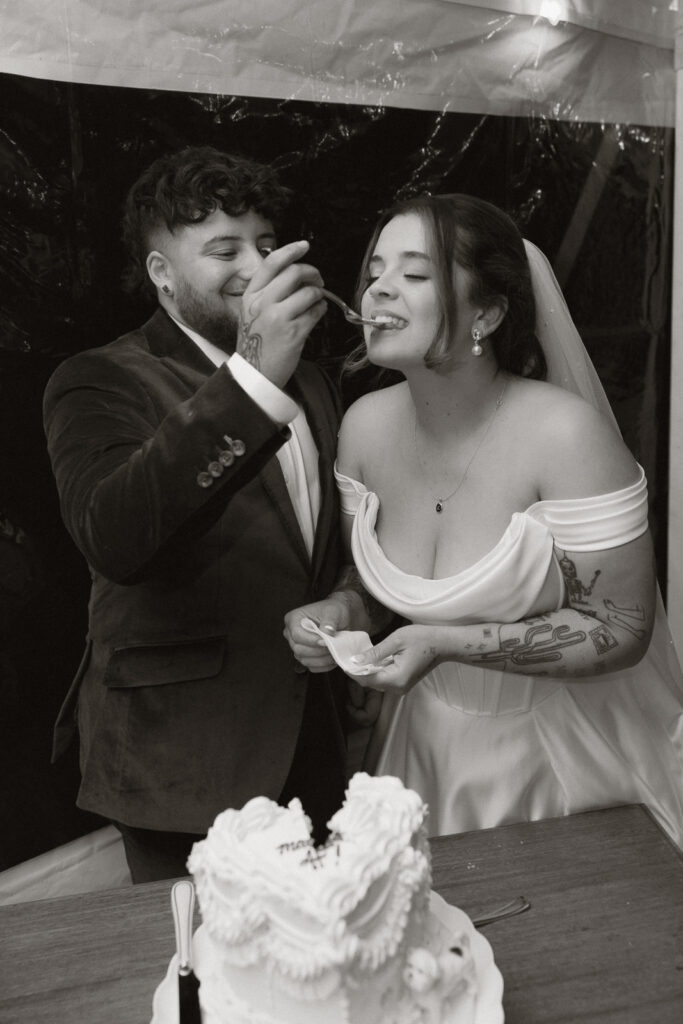 Bride and groom sharing a piece of cake during wedding reception.