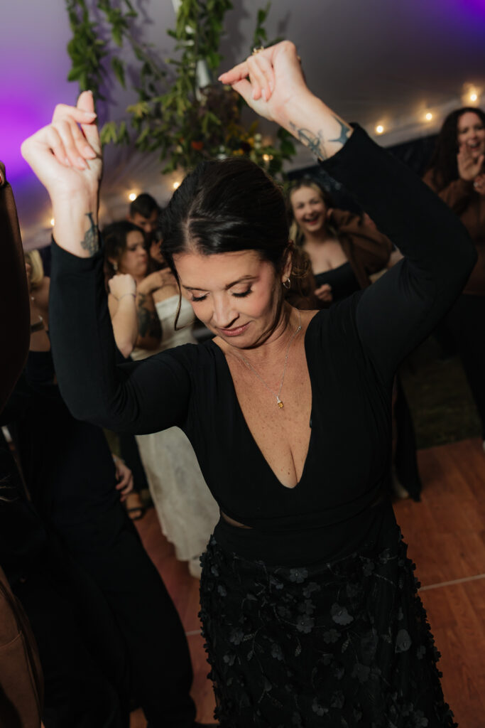 Woman dancing enthusiastically at a party, raising her arms with a joyful expression.