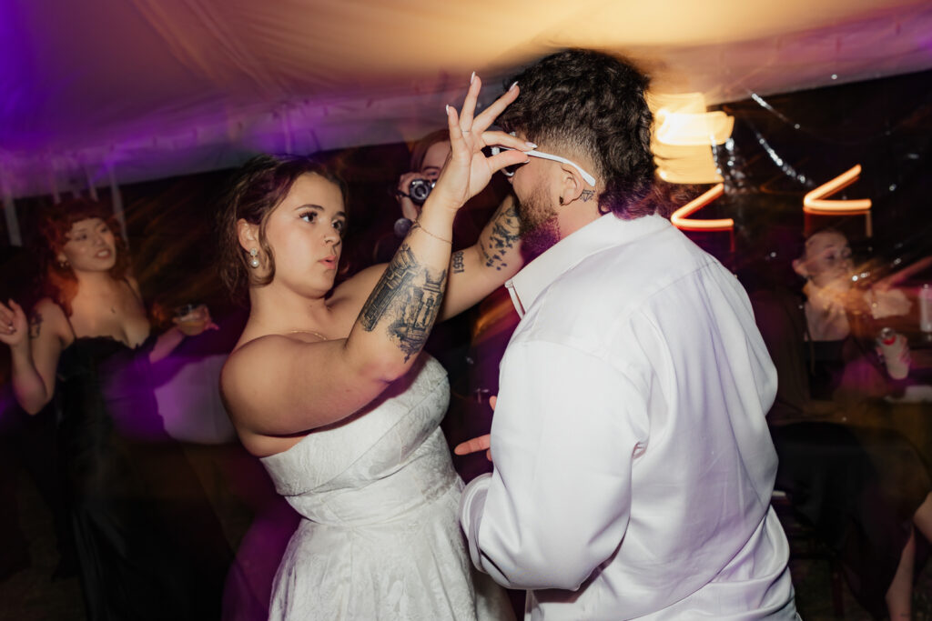 Woman in white dress fixing man's sunglasses at a party