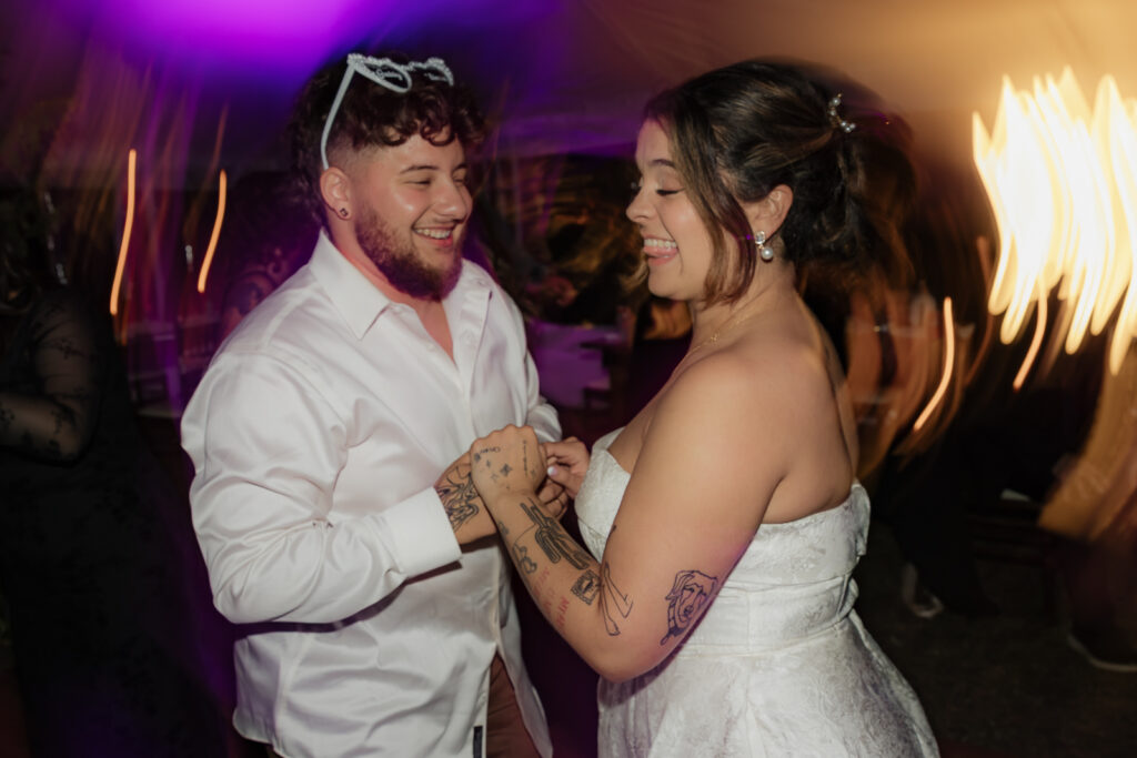 joyful couple dancing at a wedding reception with colorful lights
