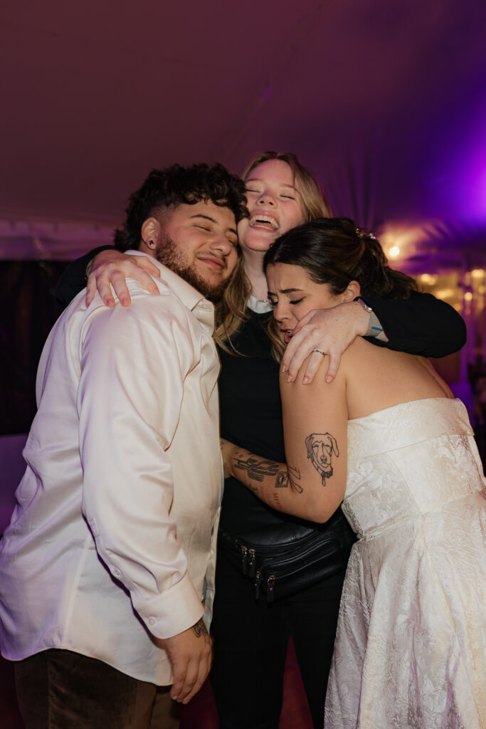 Three people embracing at an event, showing joy and friendship.