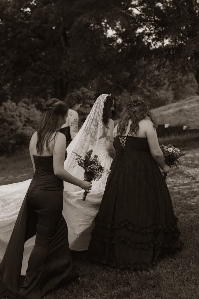 Bride in lace veil with bridesmaids outdoors