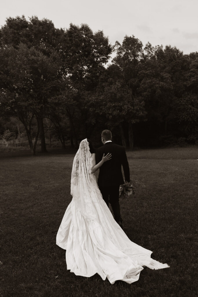 Back view of a newlywed couple walking in a park.