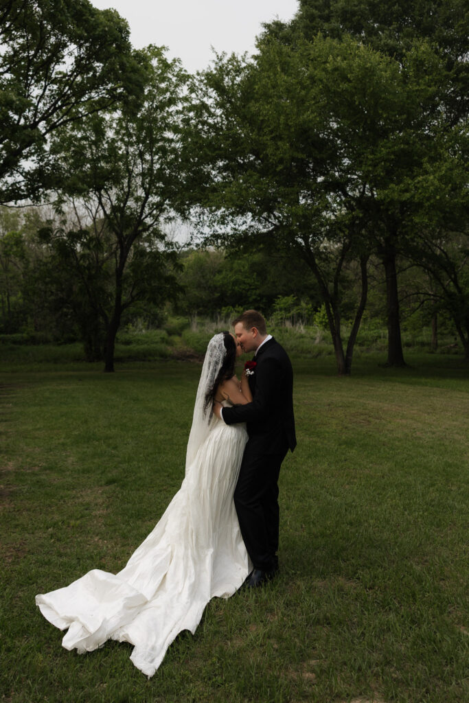 Bride and groom embrace in a lush green garden.