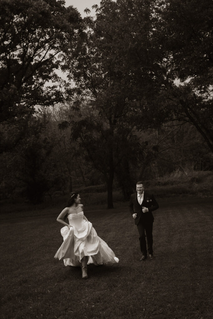 Bride and groom joyfully running through a park