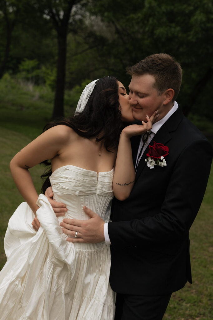 Bride kissing groom in a tender moment outdoors