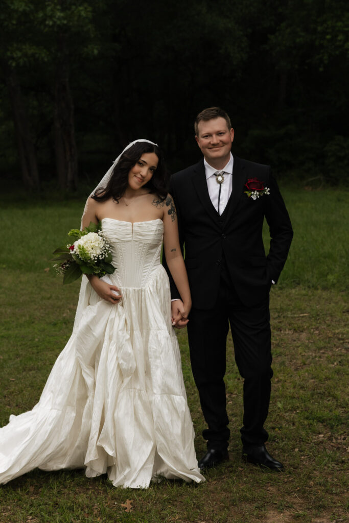 Bride and groom standing outdoors in wedding attire
