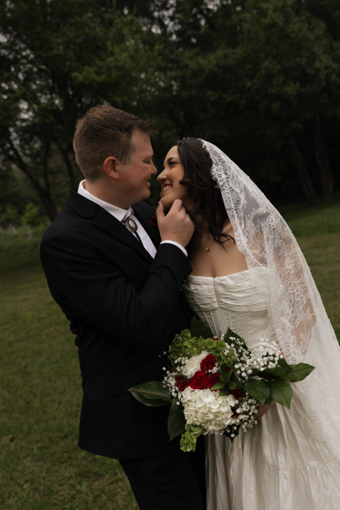 Bride and groom embracing outdoors with bridal bouquet.