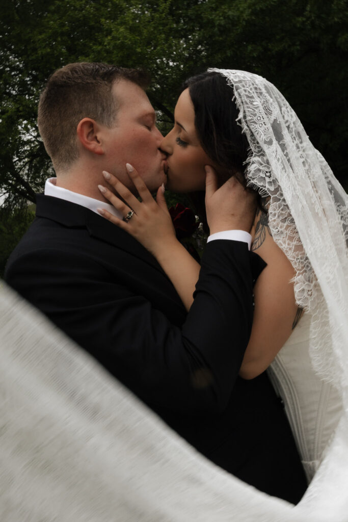 Bride and groom kissing with lacy veil