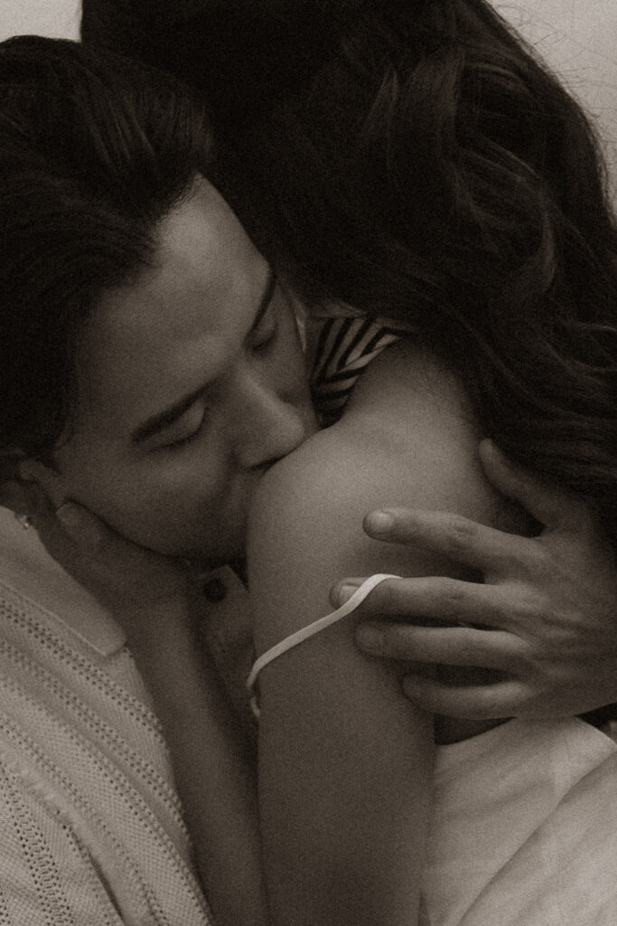 Couple embracing with man kissing woman's shoulder in vintage-style image