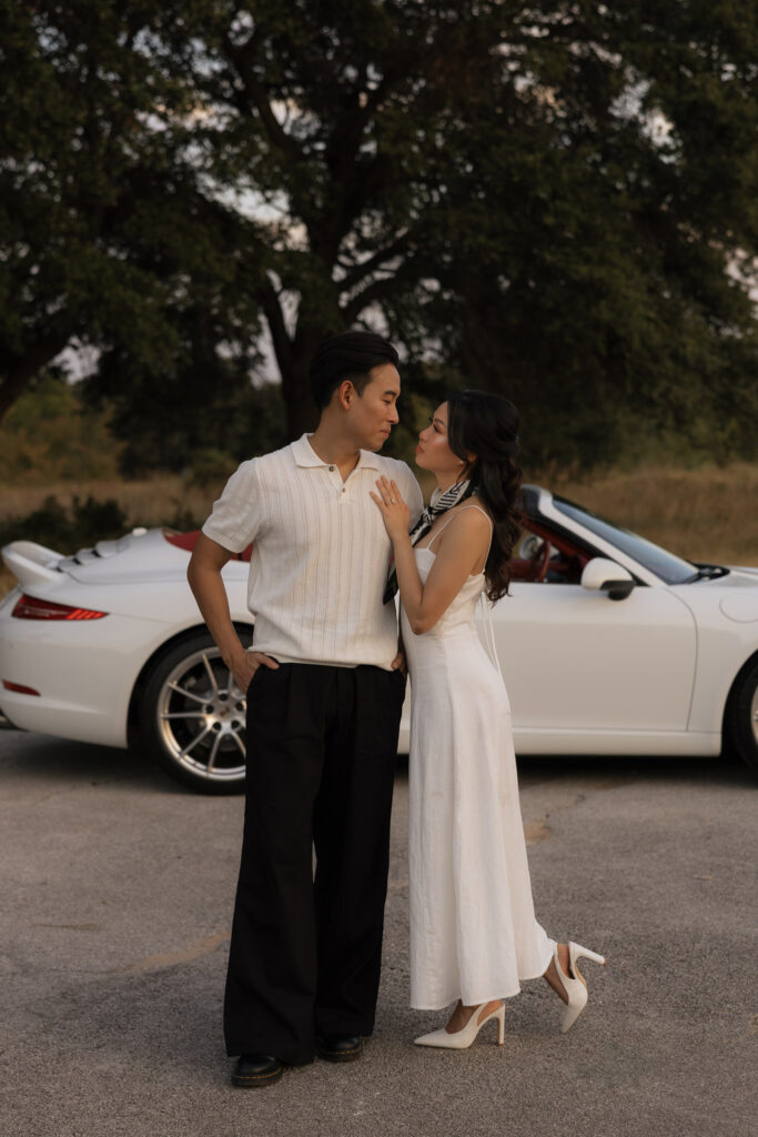 Couple posing in front of a white convertible car