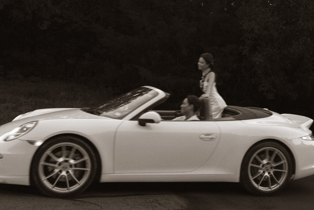 Couple riding in vintage convertible car.