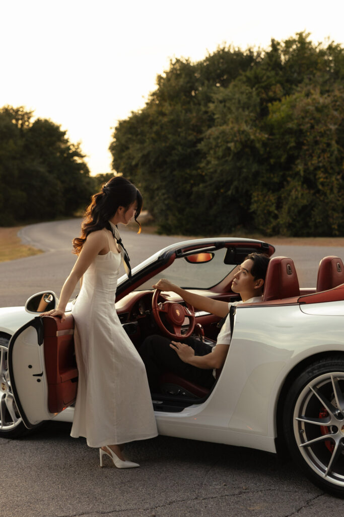 Elegant couple with sports car at sunset