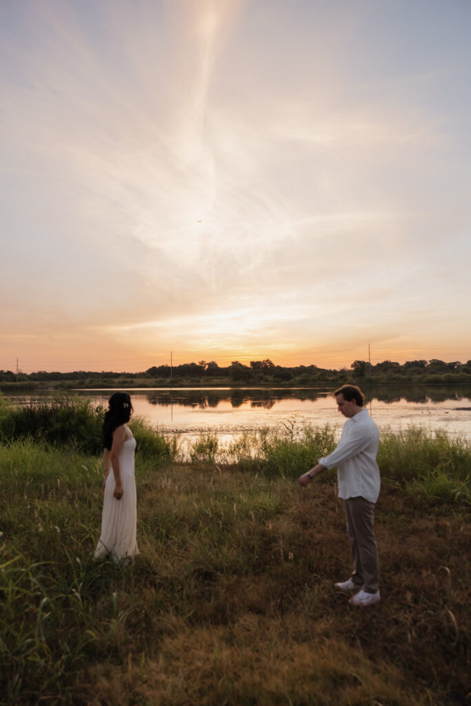 Couple standing by a lake at sunrise