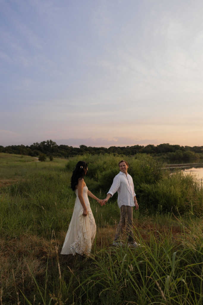 Couple holding hands by a lake at sunrise