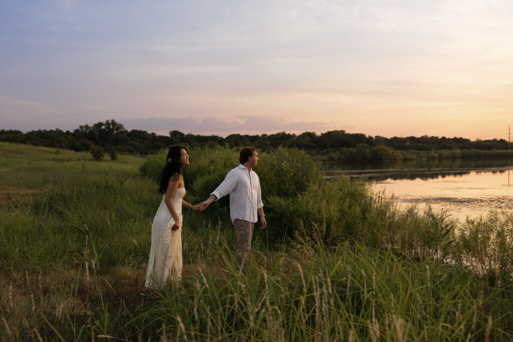 Couple holding hands by a lake during sunset