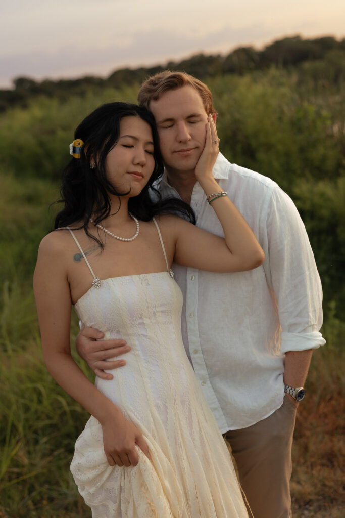 Couple embracing during a lakeside engagement at sunrise