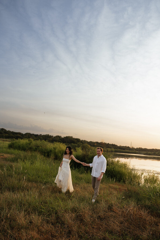 Couple holding hands by lakeside at sunrise