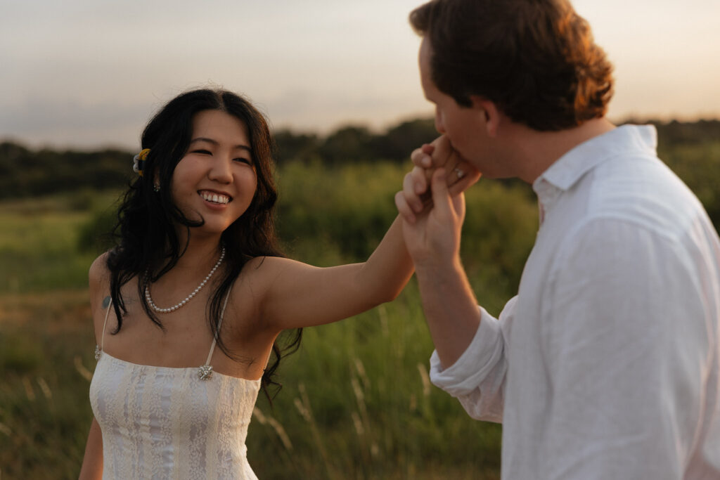 Couple celebrating engagement at lakeside during sunrise.