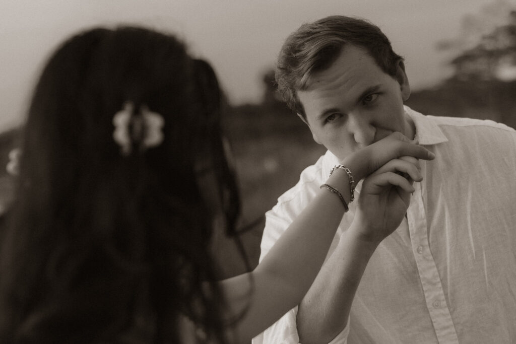Man kissing woman's hand in romantic engagement setting