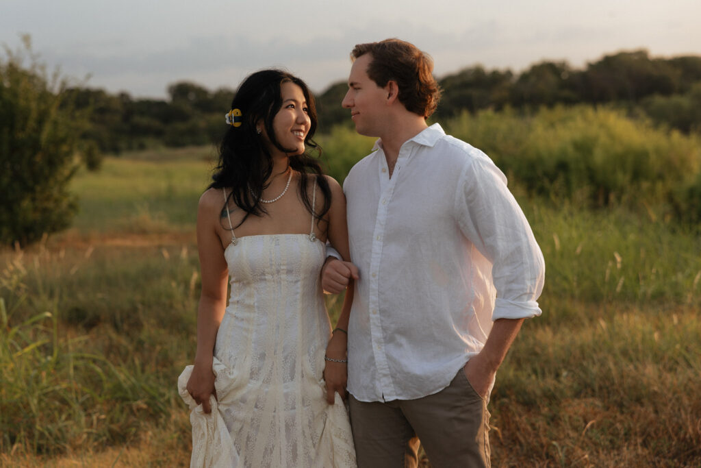 Couple in white attire walking outdoors at sunrise