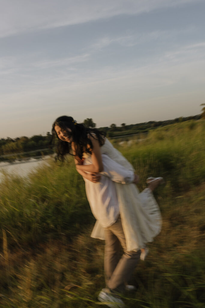 Couple enjoying a playful moment by a lakeside at sunrise