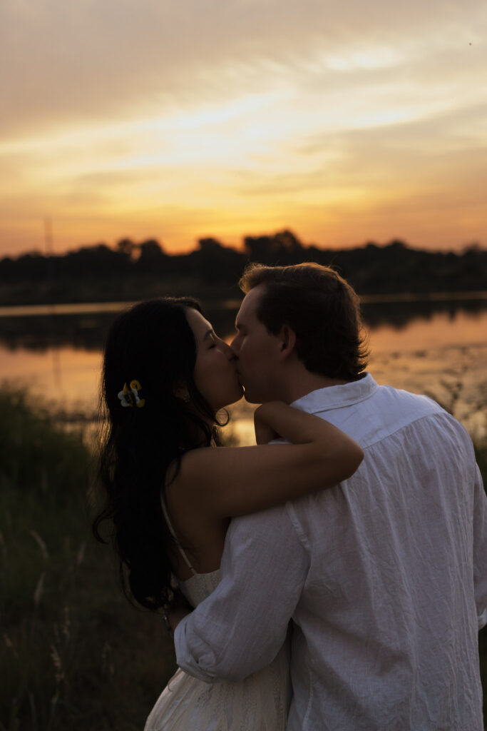 Couple kissing at lakeside during sunrise