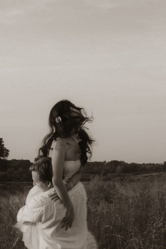 Couple embracing in a grassy field at sunrise